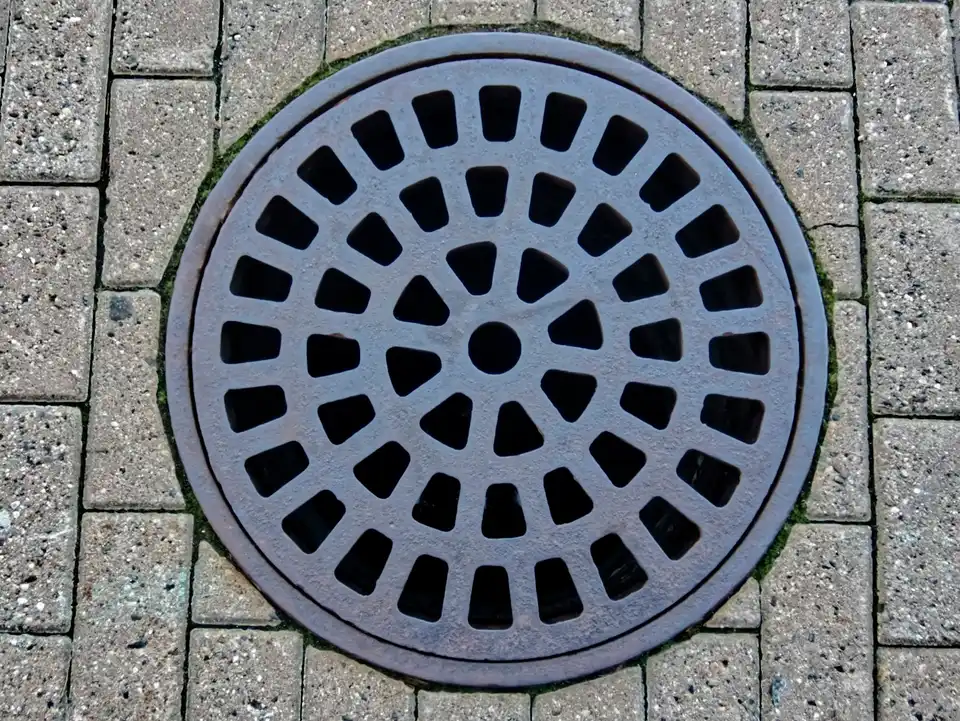 A round drain cover set in block paving